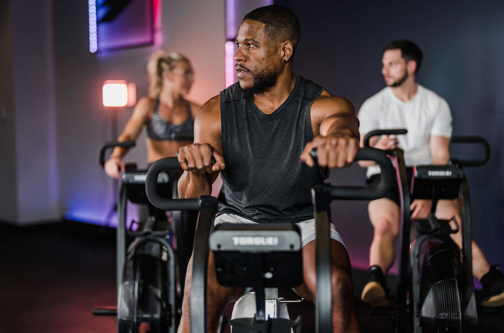 Athlete gripping the Torque Stealth Air Bike handles in a class