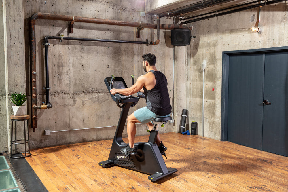 SportsArts Elite Senza Upright Cycle-13 inch C574U-13 male user exercising inside home gym 