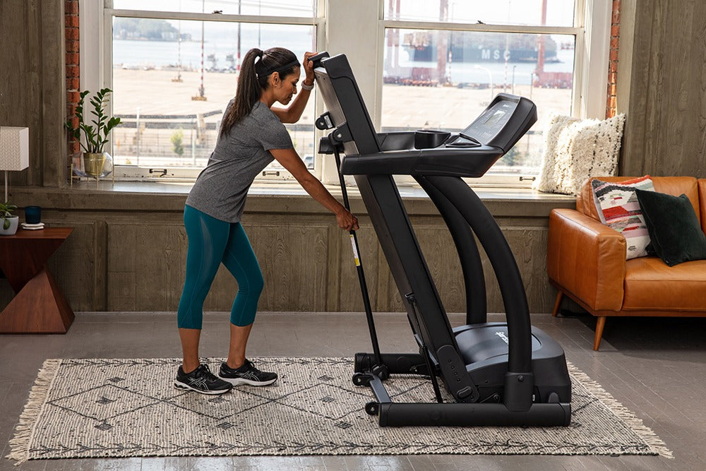 SportsArts Residential Treadmill TR22F female user adjusting the treadmill into folding postion 