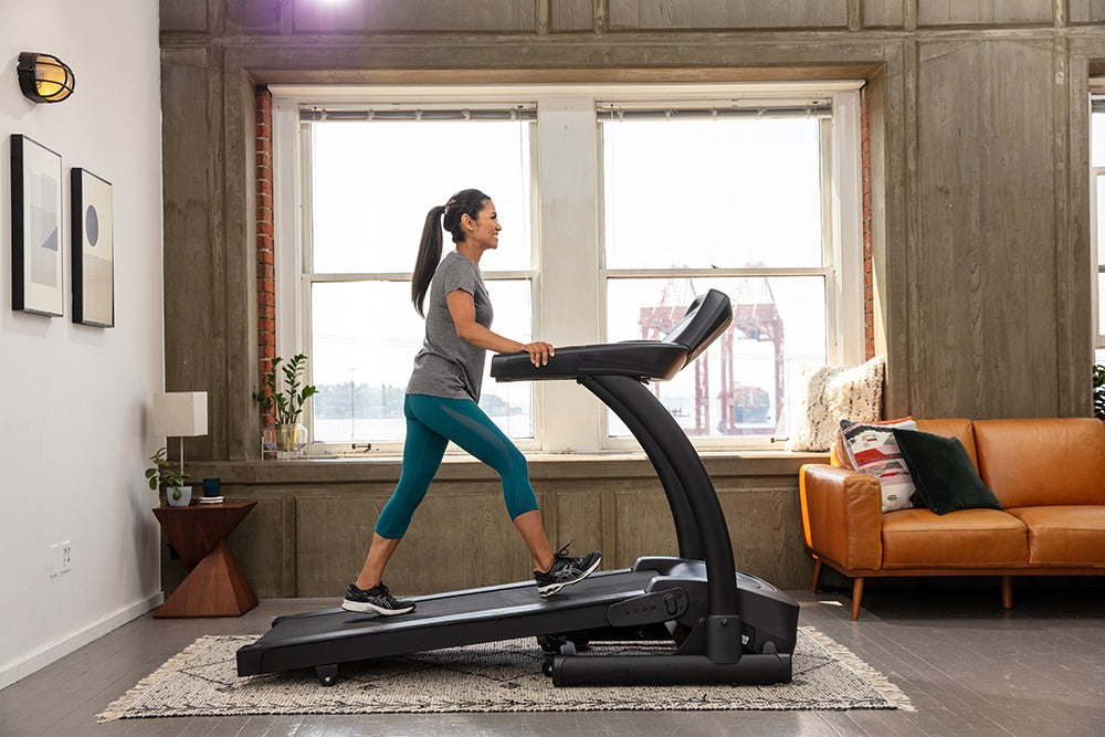 SportsArts Residential Treadmill TR22F female user walking with an incline on treadmill inisde home setting