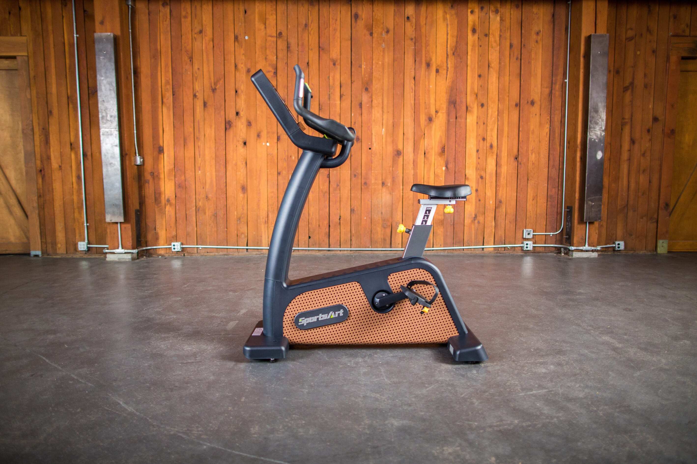 SportsArts Status Eco-Natural Upright Cycle C576U side view inside a home gym setting